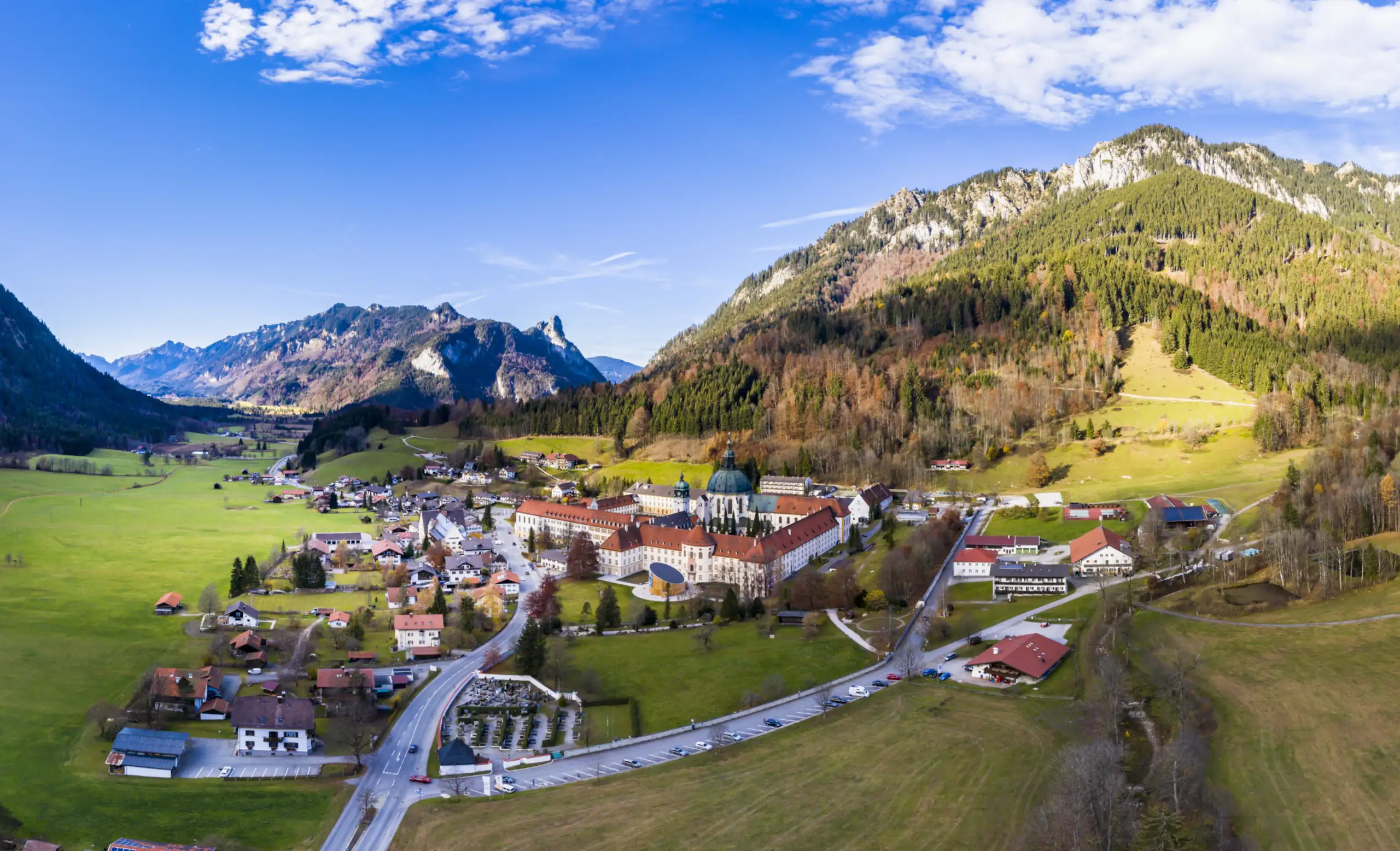 Panoramablick auf das Kloster Ettal und die umliegenden Berge in der bayerischen Natur Luftaufnahme des Klosters Ettal in Bayern, umgeben von Wiesen und Bergen, ideal für Familienausflüge in die Natur.